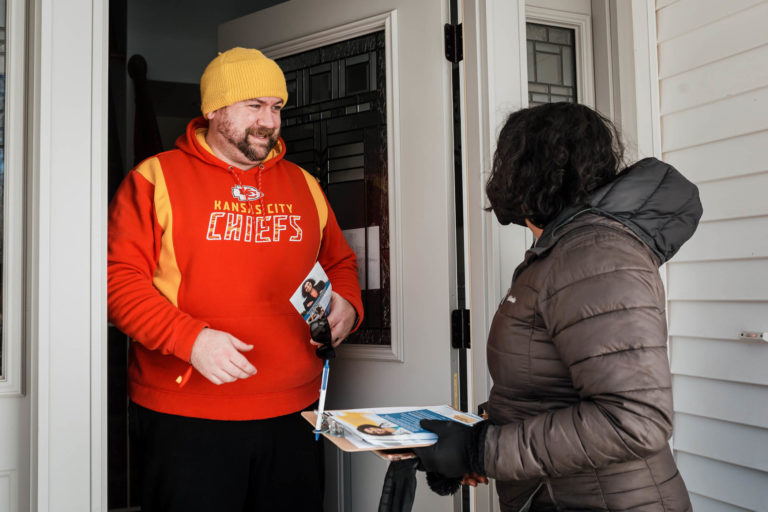 Megan Srinivas speaking with a man on his doorstep